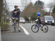 Paul Deming helps his son, Brian, 6, cross MacArthur Boulevard on March 13. Paul Deming and other cyclists have safety concerns along the corridor because of the large number of lanes and the speed of traffic.