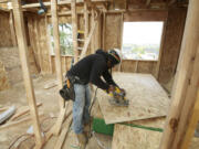 Carpenter Miguel Vargas cuts a sheet of particle board while helping build a home at the Sunrise Ridge subdivision in the Hazel Dell area.