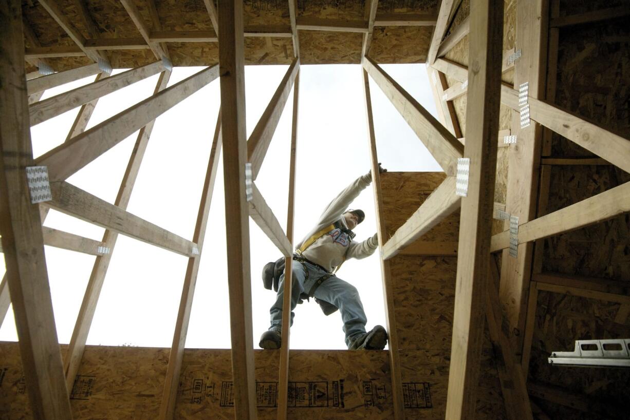 Carpenter Tony Garcia reaches for a sheet of particle board while helping build a home at the Sunrise Ridge subdivision in the Hazel Dell area.