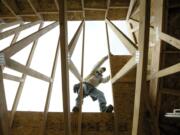 Carpenter Tony Garcia reaches for a sheet of particle board while helping build a home at the Sunrise Ridge subdivision in the Hazel Dell area.