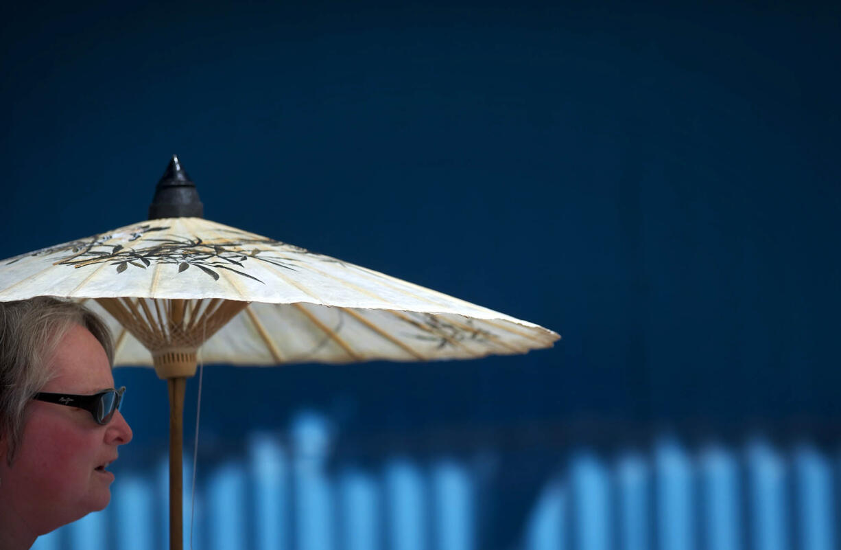 Clara Chambers walks with a parasol on Saturday while trying to keep the sun off of her at the Clark County Fair.