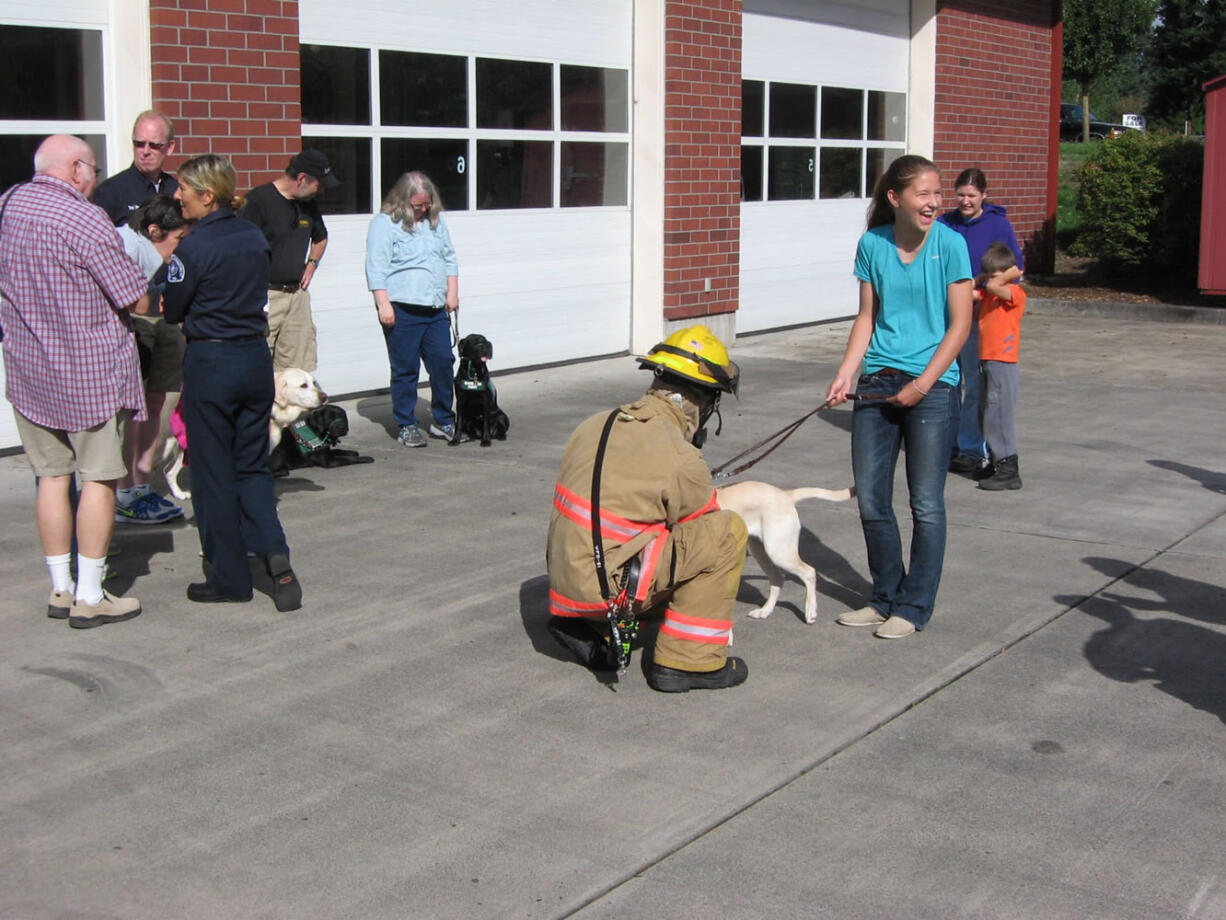 Sifton: Firefighter Greg Smith gets friendly with a future guide dog, while trainer Kristen Granger laughs it up.