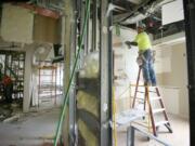 Pablo Rodriguez, right, of Harliens Drywall, removes sheetrock as part of a project to enable Legacy Salmon Creek Medical Center to handle Kaiser-insured patients once a seven-year contract takes effect Oct.