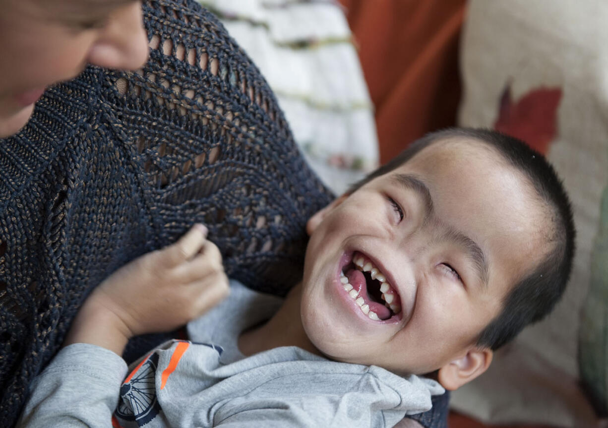 Five-year-old J, an orphan from China, laughs as he&#039;s tickled by Amanda Giese of Felida, who is fostering the boy for a four-week stay during the holidays. Giese is raising money to pay for medical appointments with specialists who can provide more information about J&#039;s medical issues, which include being born without a nose.