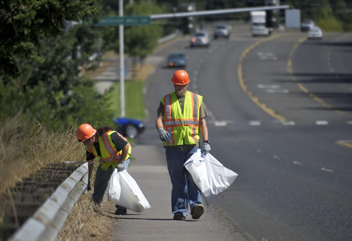 Vancouver residents Jason Kraft, 40, left, and Michael McCoy, 35, pick up trash Tuesday along Fourth Plain Road as part of an offender work crew.