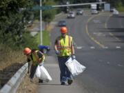 Vancouver residents Jason Kraft, 40, left, and Michael McCoy, 35, pick up trash Tuesday along Fourth Plain Road as part of an offender work crew.