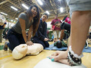 Photos by Steven Lane/The Columbian
Chelsea Labitad, 18, left, a senior at Evergreen High School,  receives a hands-only CPR training session Friday from Fire District 6 public education coordinator Sarah Mitchelson. Several hundred students received a short orientation and then hands-on training with mannequins.