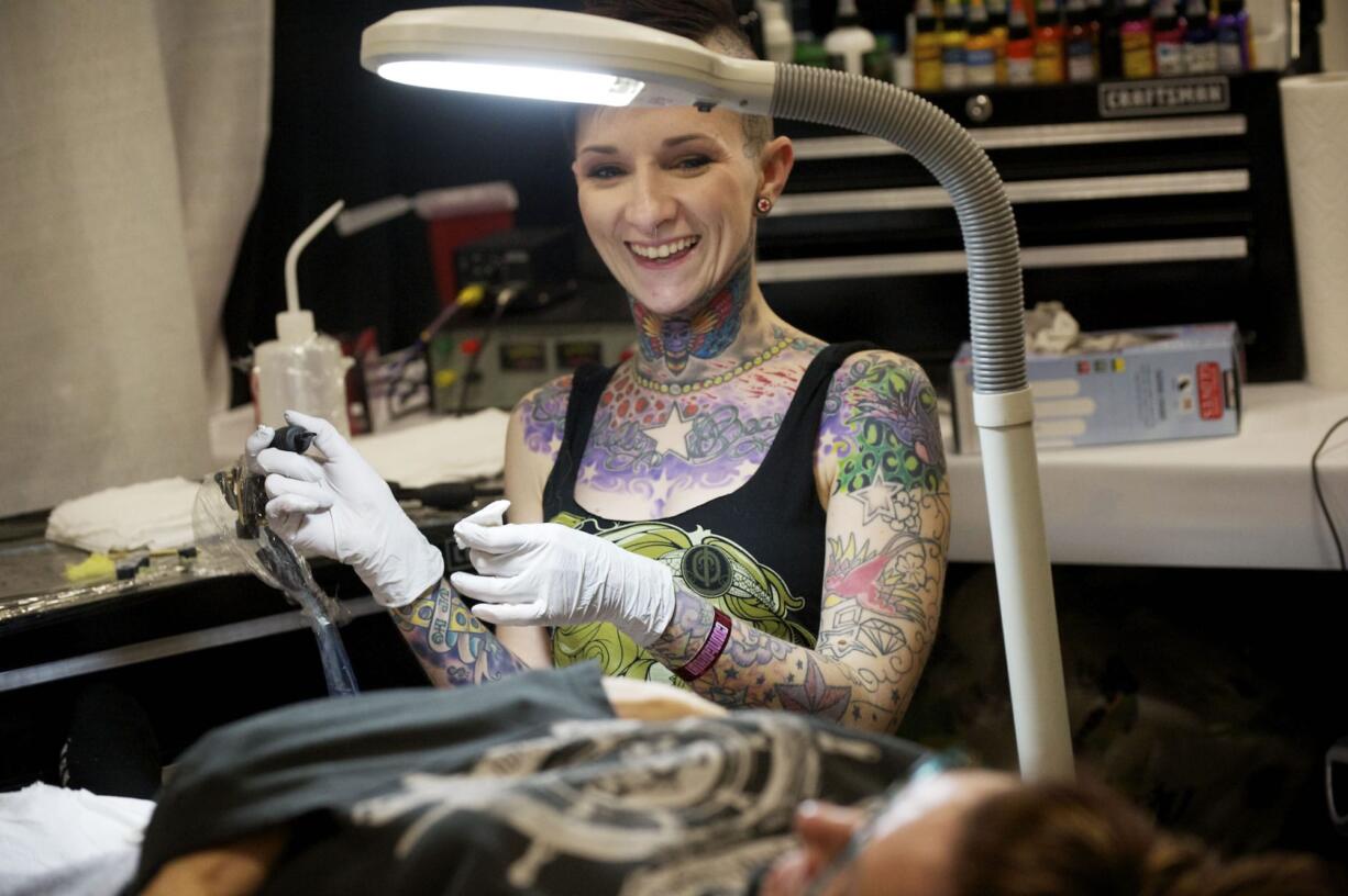 Tattoo artist Amanda Midland of Five Star Tattoo Company in Battle Ground takes a break from etching a tattoo on her mother, Susan Midland of Vancouver, during Sunday's Body Art Expo at the Clark County Event Center at the Fairgrounds.