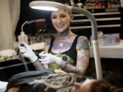 Tattoo artist Amanda Midland of Five Star Tattoo Company in Battle Ground takes a break from etching a tattoo on her mother, Susan Midland of Vancouver, during Sunday's Body Art Expo at the Clark County Event Center at the Fairgrounds.