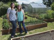 Omni Grover, right, and her best friend Kati Elliott stand next to Grover's urban garden, which includes a small greenhouse. The city cited Grover for the greenhouse because it's not in a backyard, but, with Elliott's help, she took the case to the Vancouver City Council and won. Consequently, rules regarding hobby greenhouses may be relaxed.