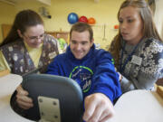 Luke Ashe is encouraged and lifted into a standing frame by Donelle Rodriguez, left, a physical therapy assistant, and Cassie Williams, a rehabilitation technician, during physical therapy Tuesday at Pacific Specialty and Rehabilitative Care in Vancouver. Luke stands, with help from the device, for 10 minutes to increase his endurance and strengthen his trunk muscles. Ashe was found in a coma Jan. 15.