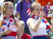 Abby Storm, 14, waves her flag as Rachel Storm, 17, photographs the parade.