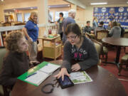 Marion Kelly, 92, left, looks to Covington Middle School eighth-grader Olivia Adams, 13, for advice on using her Kindle Fire at Kamlu Senior Living Center Monday morning.