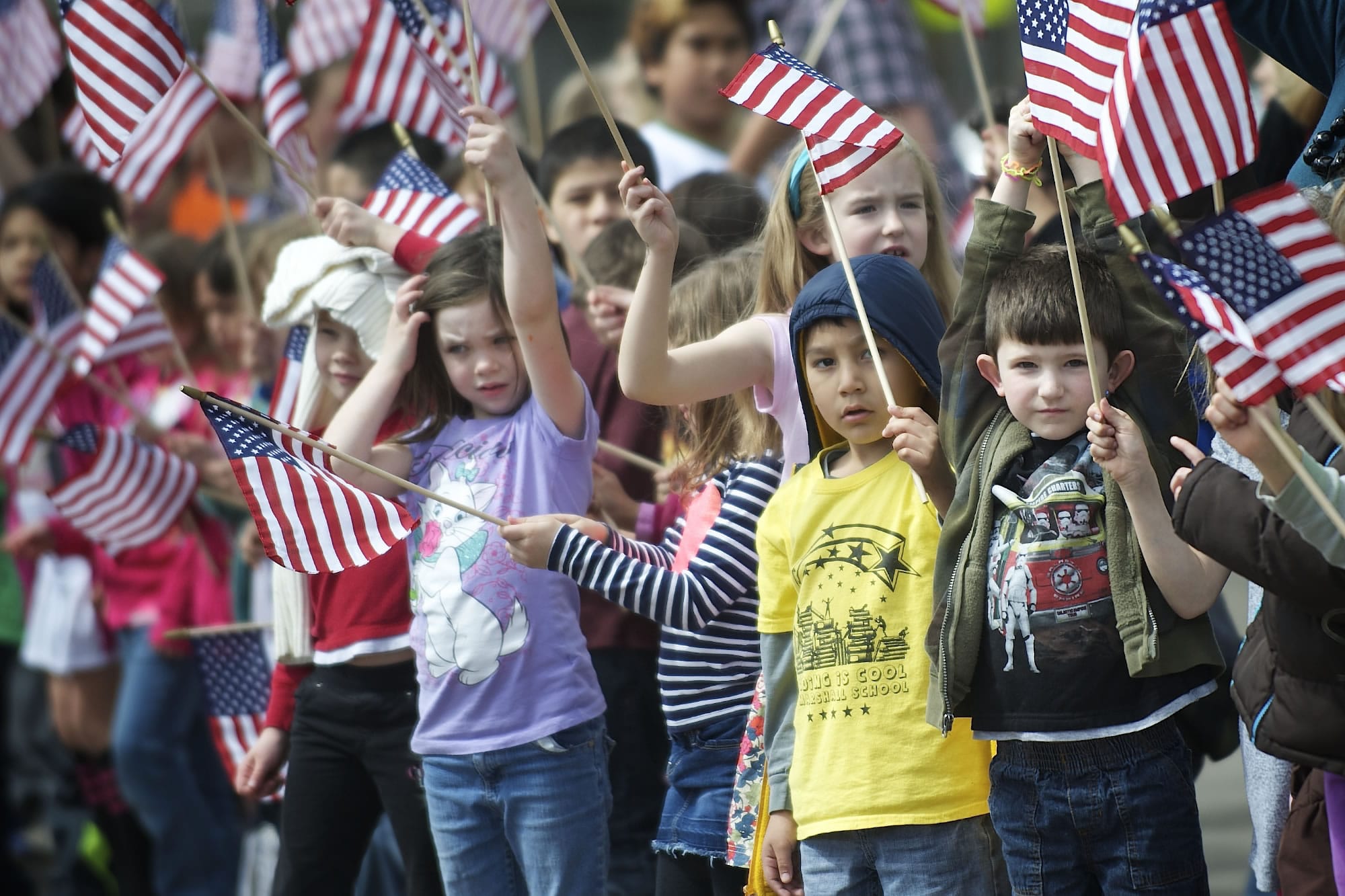 Students at Marshall Elementary School wave American flags as they say goodbye to retired U.S.