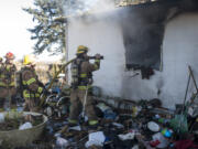 Firefighter Chase Christopher mans a hose as he and others battle a fire in a house in Battle Ground on Thursday.