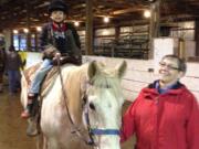 Brush Prairie: Volunteer Sara Jackson guides a boy as he rides a horse at Silver Buckle Ranch's Dec.