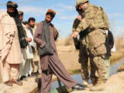 North Image: U.S. Army Capt. Jude Mazzotta, from Vancouver, discusses a hydroelectric power plant system during a Dec. 6 assessment visit to Kawri, Afghanistan. A 22-year-old contractor, Shafiqullah, center, built the system that provides power to 25 families in the remote village.