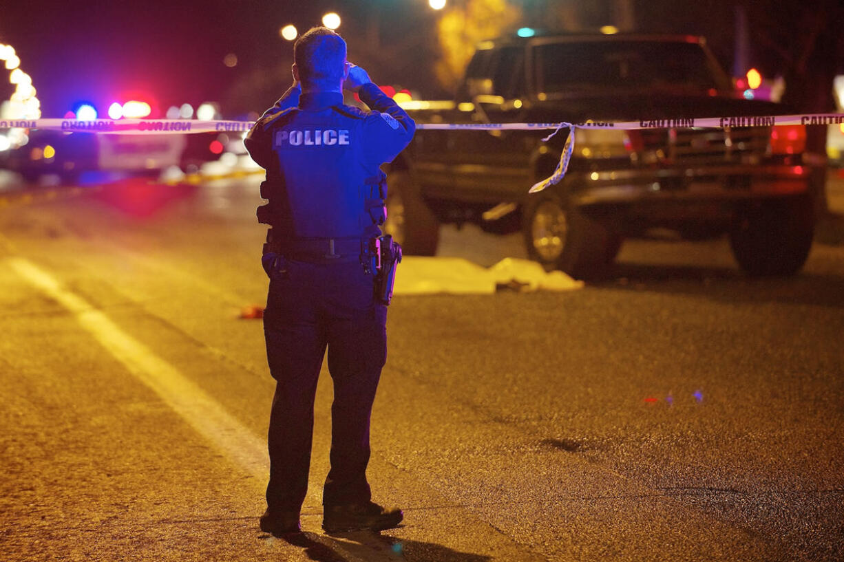 A Vancouver police officer takes photos of the scene where a man was struck by a pickup and killed Monday evening while crossing East Mill Plain Boulevard near Andresen Road.