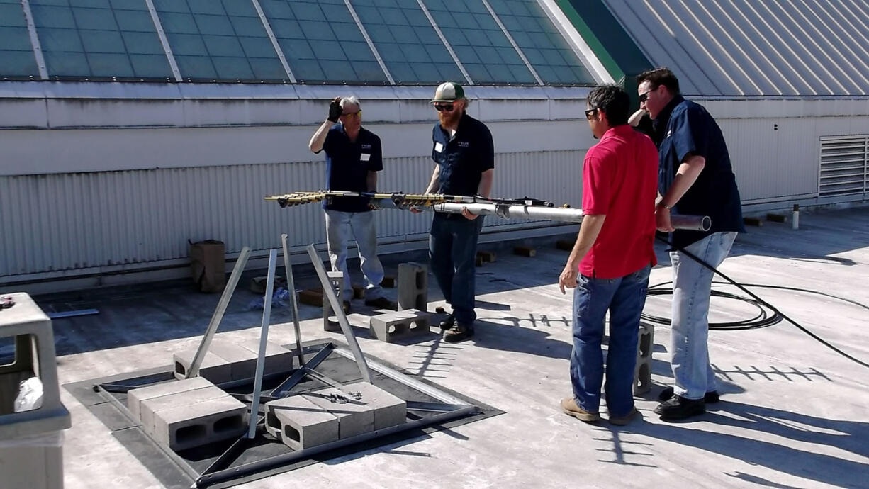 Dave Behrens, from left, Matt Bryant, Heron Jacobson and Brian Audiss of Silke Communications install a repeater and antenna system at Skyview High School that provides in-building penetration and wide area coverage to the school and the district.