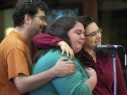 Jason Covington, a volunteer with OneAmerica Vancouver, left, and family friend Loriann Whalen, right, comfort Natasha Derthick, center, as she gives an emotional presentation on immigration reform at St. John the Evangelist Catholic Church in Vancouver. Derthick's sister, Karen Byrne, a native of Ireland who spent much of her childhood in Vancouver, is unable to live near her family in Clark County because of delays in the U.S. immigration system.