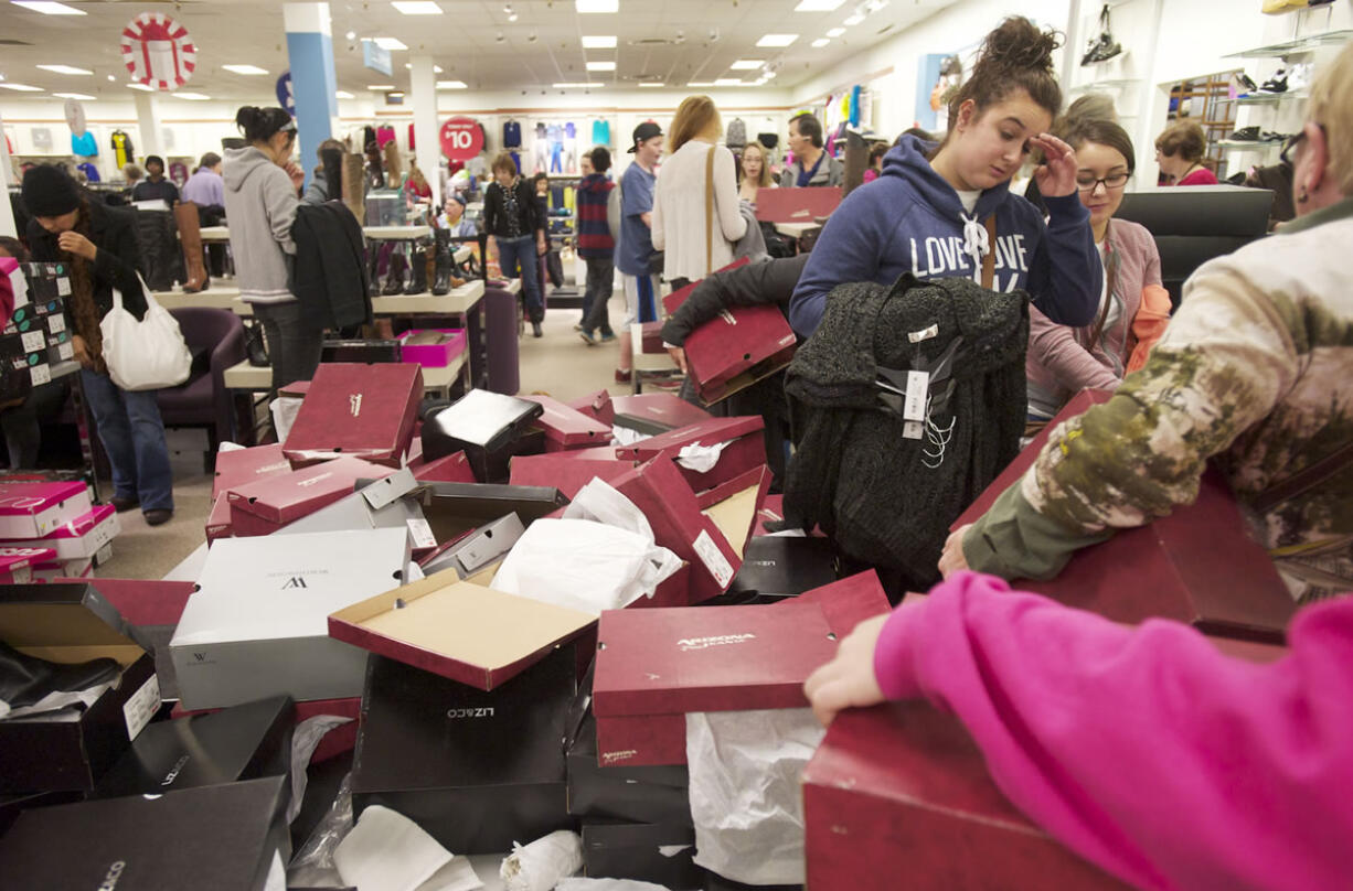 Bargain-hunting Black Friday shoppers rifle through a display of specially priced fashion boots in J.C.