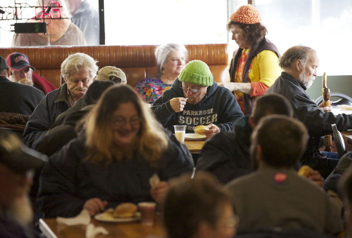 Mark Kemp of Portland, wearing the green cap, finishes his plate at Chronis' free Thanksgiving meal.