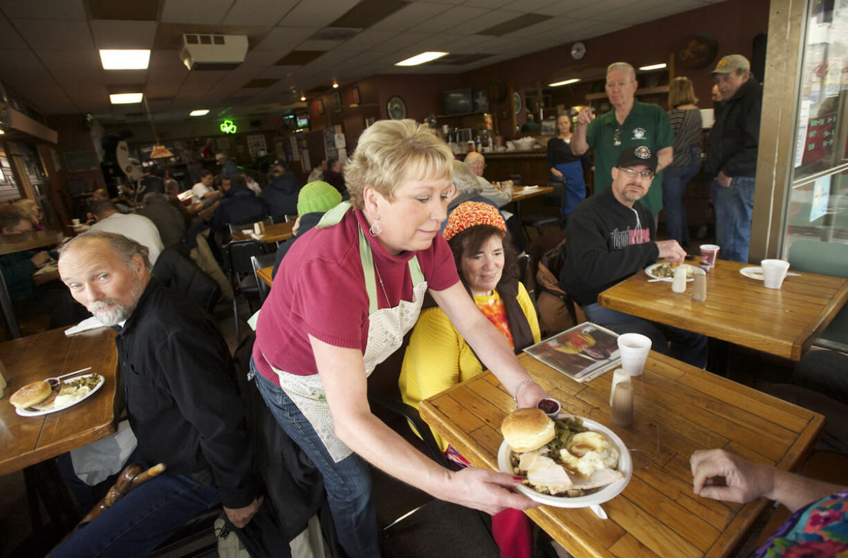 Volunteer Mickey Giese serves a guest at Chronis' Restaurant's free Thanksgiving meal Thursday.