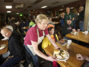 Volunteer Mickey Giese serves a guest at Chronis' Restaurant's free Thanksgiving meal Thursday.