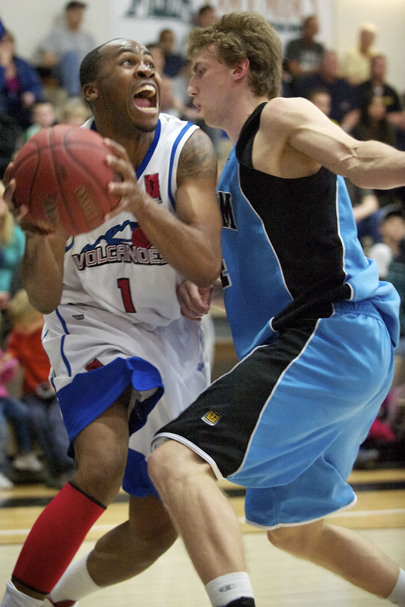 Mike Ward (1) of the Vancouver Volcanoes drives to the basket against Chas Kok, (24) of the Bellingham Slam during the Volcanoes home opener on Sunday at Clark College.