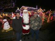 Randy Peppers, from left, David Buffum (dressed as Santa) and Paul Lamb have a friendly competition to show who can put up the most elaborate Christmas decorations at their homes on Southeast Riveridge Drive.