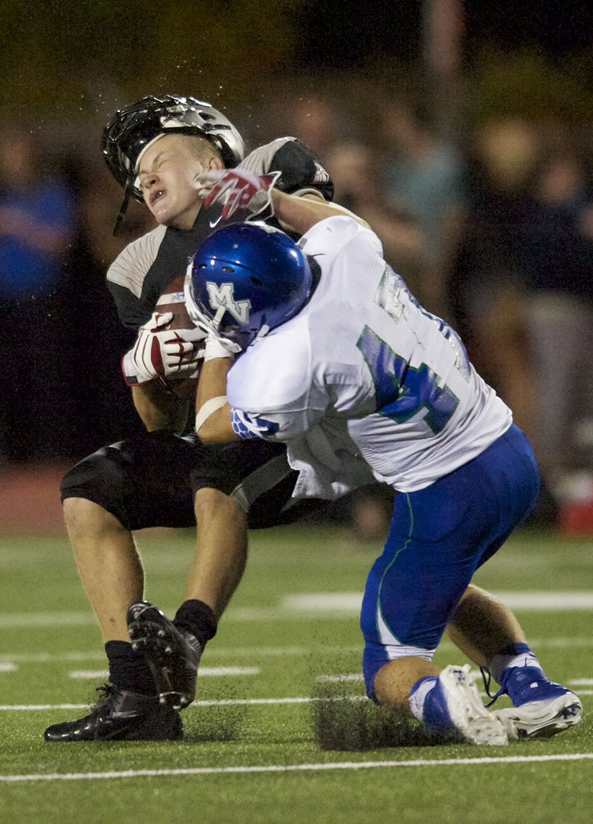 Steven Lane/The Columbian
Union receiver Trent Cowan, left, has his helmet knocked off by Mountain View defender Russel Culverwell but manages to hang onto the ball for a 16-yard gain at McKenzie Stadium. The Titans scored on the drive in their win.