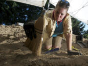 Portland State University archaeology student AlyssA Kudray, 25, whisks away soil July 10 in a dig at the Fort Vancouver National Historic Site.