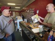 Brian Wassman, right, owner of Everybody's Music, explains the history of a record album's photo cover to customer Chip Bedord at the record store in Uptown Village he opened in 1992.