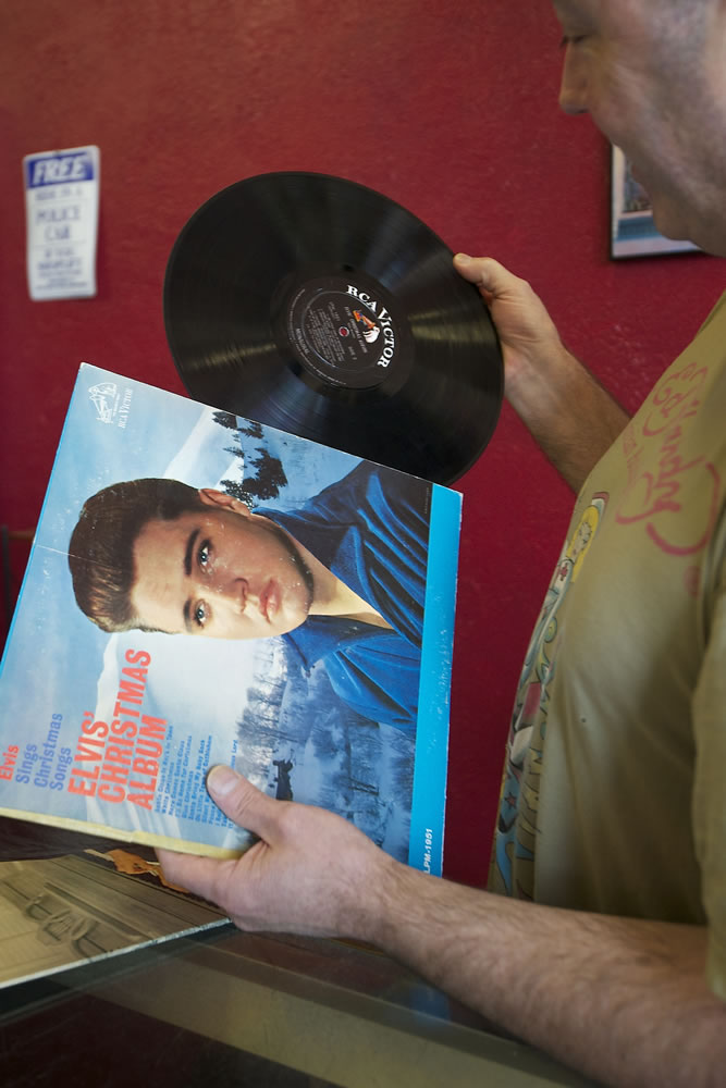 Brian Wassman checks the condition of an Elvis Presley album at Everybody's Music, an Uptown Village record store Wassman has listed for sale after owning and operating it for nearly 22 years.