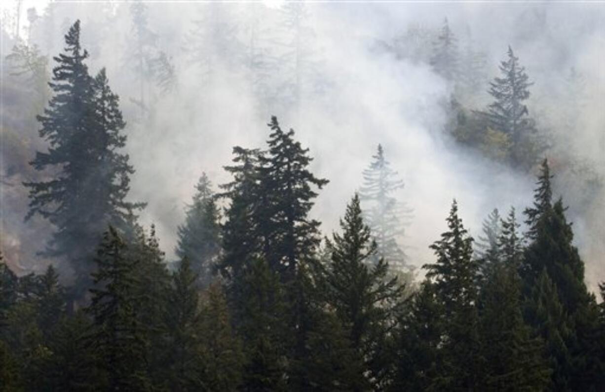 Fire smolders in the forest along Hwy. 141 near Bingen, Wash., causing concern to home and property owners, Thursday, Sept. 6, 2012. A total of about 450 houses are threatened by the fire, and most of those residents have been told to be ready to flee if the fire heads their way.