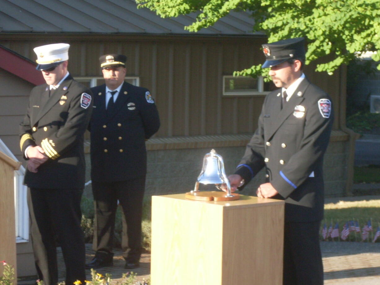 Cliff Free, division chief of emergency medical services with the Camas-Washougal Fire Department, pauses as Firefighter/Paramedic Ben Silva rings a bell and retired Fire Capt. Larry Saari looks on in front of C-W Fire Station 171, in Washougal, Wednesday morning. The tribute to the thousands of people who died as the result of terrorists' acts Sept. 11, 2001 included comments from Free, Saari, Fire Chief Nick Swinhart and Washougal Mayor Sean Guard. &quot;Twelve years ago, a horrible act happened to our great nation,&quot; Saari said. &quot;Today we will have time to think about all those who were lost, far too early in life and of the heroes who did what they had to do to save so many lives.&quot; Trumpet player Isaac Hodapp, a sophomore at Camas High School, performed &quot;Taps.&quot; After the ceremony, a complimentary breakfast was provided by members of the East Clark Professional Firefighters. Saari and staff members placed more than 300 small American flags along the entryway to the fire station Tuesday.