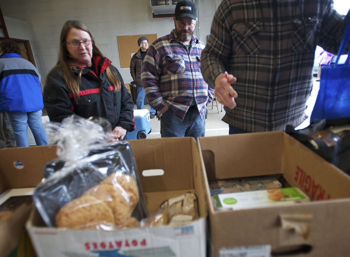 Deborah Schitz, left, and Cark Hawes, center, of La Center, pick up food  Jan.