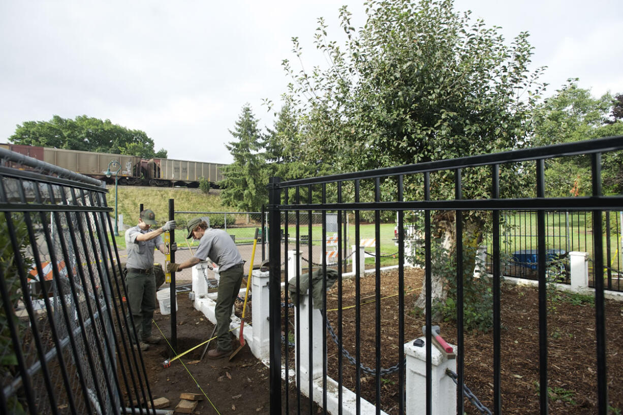 National Park Service employees Stephen Phelan, left, and Cary Porter set a fence post Thursday at Vancouver's Old Apple Tree Park.