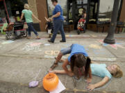 Sophie Albright, 8, uses chalk to trace around her friend, Chloe Schafer, 5, during the second annual Chalk the Walks, a project of the Joy Team. Top: Jay Morton, 24, a 2006 graduate of Vancouver School of Arts and Academics, works on a chalk drawing on an Uptown Village sidewalk.