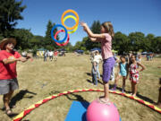 Ellie Johnson, 8, plays a hoop game with Bill Hewitt of Circus Cascadia while balancing on a ball at John Ball Park during the Sunday Streets Alive event.