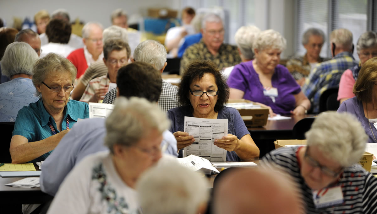 Election workers inspect ballots on Tuesday at the Clark County Elections Office in Vancouver.