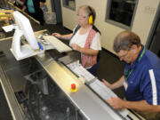 Election officers including Wendy Wimer, top, run the machine for sorting ballots at the Clark County Elections Office in Vancouver on Tuesday.