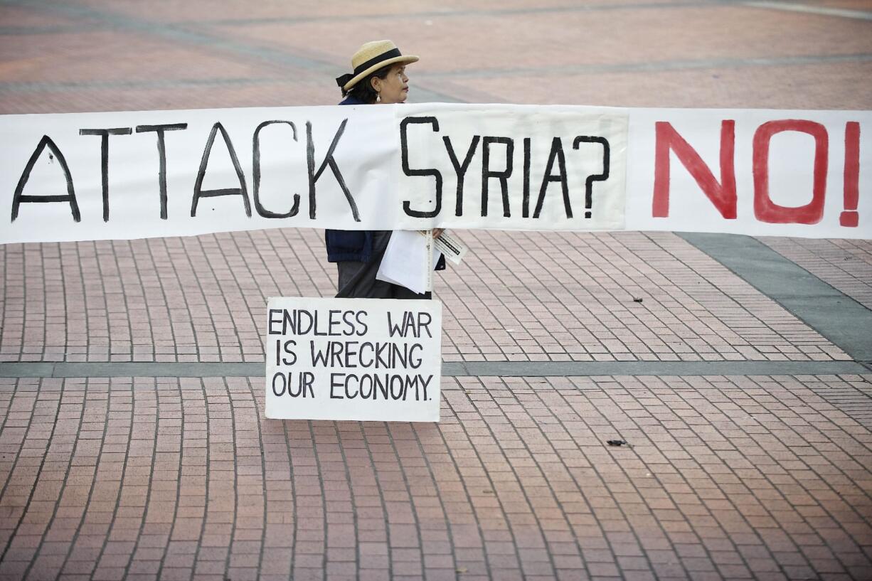 Darlene Edwards of Vancouver holds a sign Monday evening at a gathering of concerned citizens against the use of military action in Syria. The rally was in Vancouver's Esther Short Park. The sign previously read &quot;Attack Iraq?