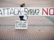 Darlene Edwards of Vancouver holds a sign Monday evening at a gathering of concerned citizens against the use of military action in Syria. The rally was in Vancouver's Esther Short Park. The sign previously read &quot;Attack Iraq?