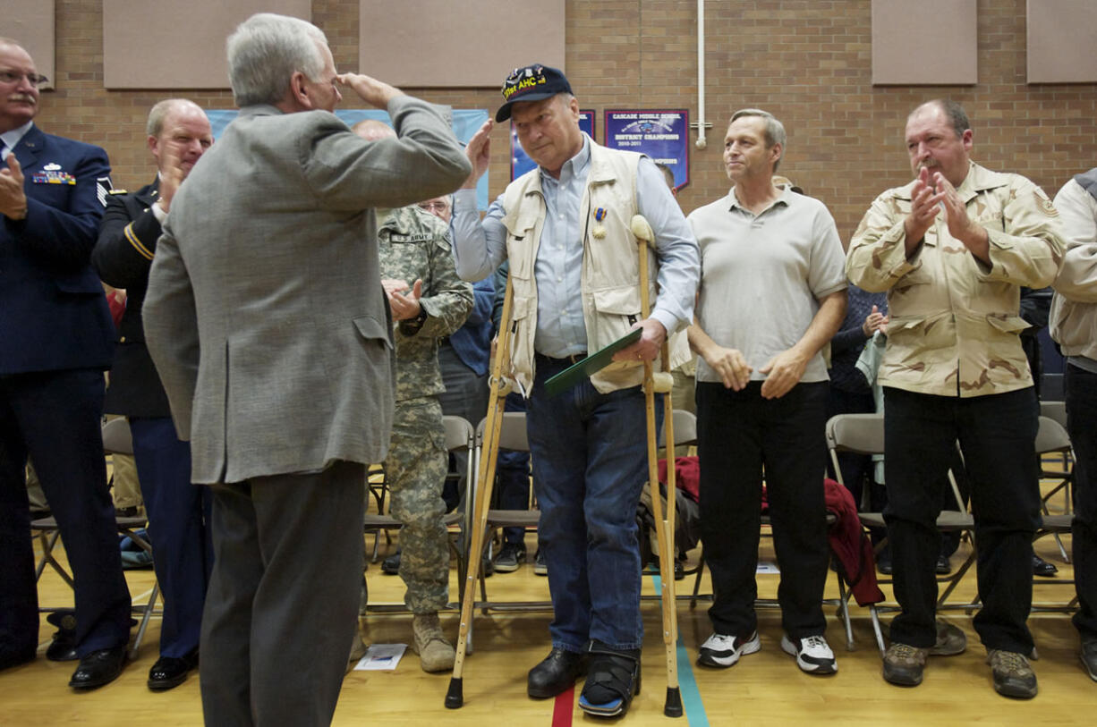 Former helicopter pilot Aaron Rich, center, salutes rescue pilot Don Torrini after receiving an Army Air Medal he earned in 1968.