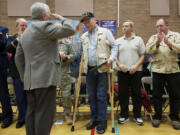 Former helicopter pilot Aaron Rich, center, salutes rescue pilot Don Torrini after receiving an Army Air Medal he earned in 1968.