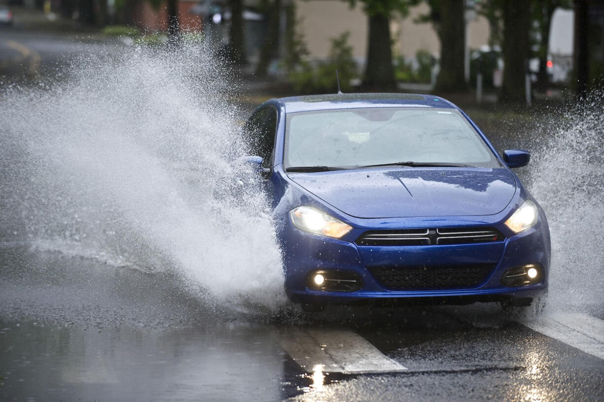 A car negotiates standing water Sunday on Columbia Street at East Mill Plain Boulevard.