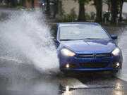 A car negotiates standing water Sunday on Columbia Street at East Mill Plain Boulevard.