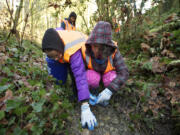 Kendall Record, 16, left, Frances Calvin, 13, right, and Kaliyah Davis, 14, background, spent Monday morning digging garbage and broken glass out of a dry creek bed in Vancouver's Blandford Canyon.