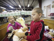 Emilia, 5, and Chico, 4, play with stuffed animals as their mom, Jessica Fraly, looks for school clothing at the St. Vincent de Paul food and clothing bank.